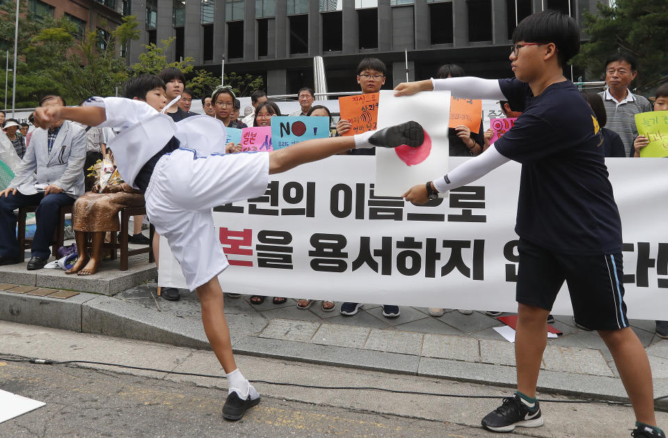 A South Korean elementary school student kicks a plastic plate showing a Japanese flag during a rally to denounce Japan's trade restrictions on South Korea in front of the Japanese embassy in Seoul, South Korea, Thursday, Aug. 8, 2019. Japan has granted the first permit for South Korea-bound shipment of chemicals for use in high-tech materials under Tokyo's new export requirement that has increased tensions with Seoul. (AP Photo/Ahn Young-joon)