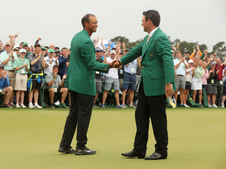 Golf - Masters - Augusta National Golf Club - Augusta, Georgia, U.S. - April 14, 2019. Tiger Woods of the U.S. shakes hands with last year's champion Patrick Reed of the U.S. as he is presented with his green jacket after winning the 2019 Masters. REUTERS/Jonathan Ernst