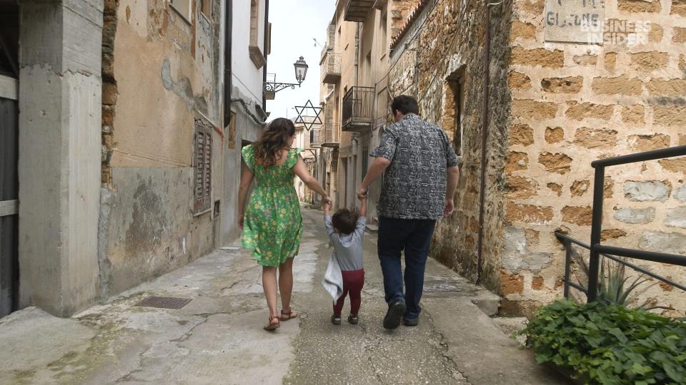 Gary and Tam Holm walking with their child in Sicily.