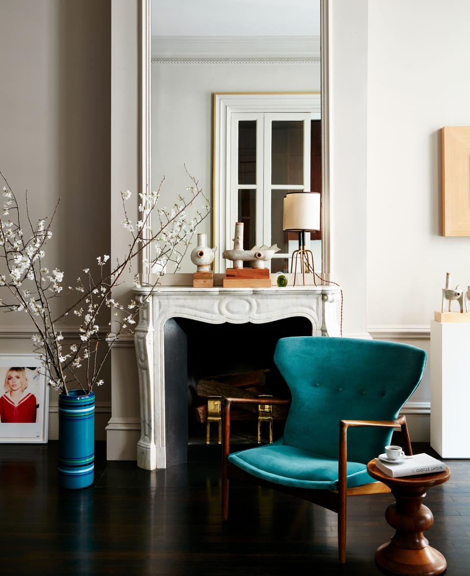 Beside a mantel in a corner of the dining room is a vintage Scandinavian lounge chair with a teak frame, upholstered in teal blue cashmere velvet from Pierre Frey.