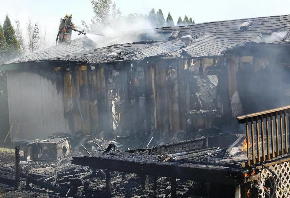 A firefighter works from a ladder to spray the smoldering attic of a home in West Richland in 2018.