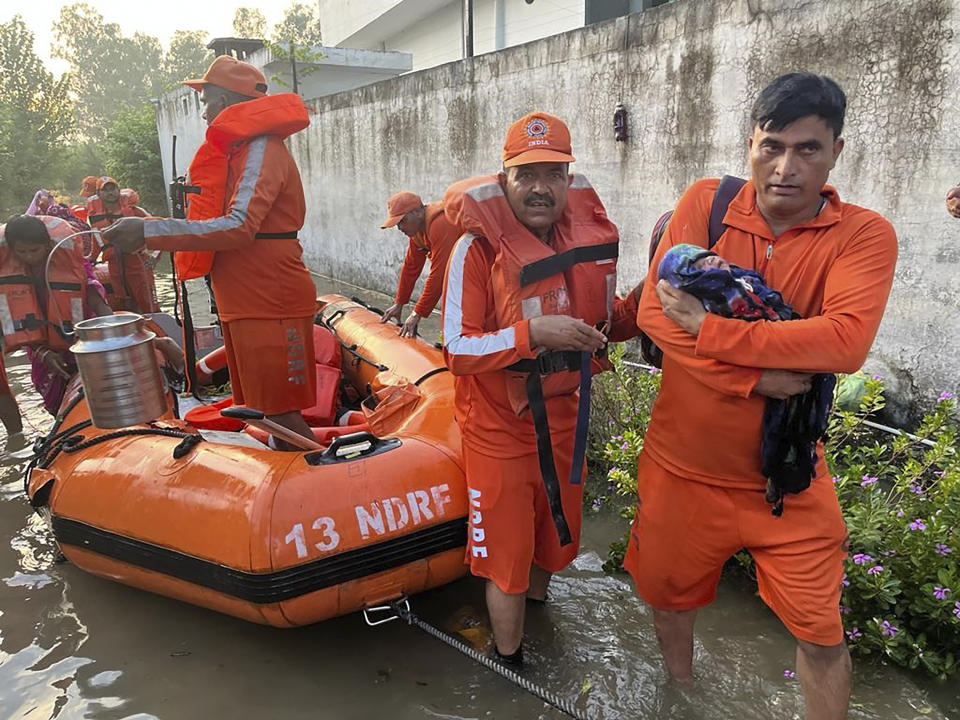 In this photo made available by the National Disaster Response Force (NDRF) on Aug. 15, 2023, an NDRF personnel carries an infant to safety in flood-affected Himachal Pradesh state, India. Days of relentless rain in India’s Himalayan region have killed more than 70 people this week, a government official said Thursday, as a heavy monsoon triggered landslides and flash floods that have submerged roads, washed away buildings and left residents scrambling for safety. (National Disaster Response Force via AP)