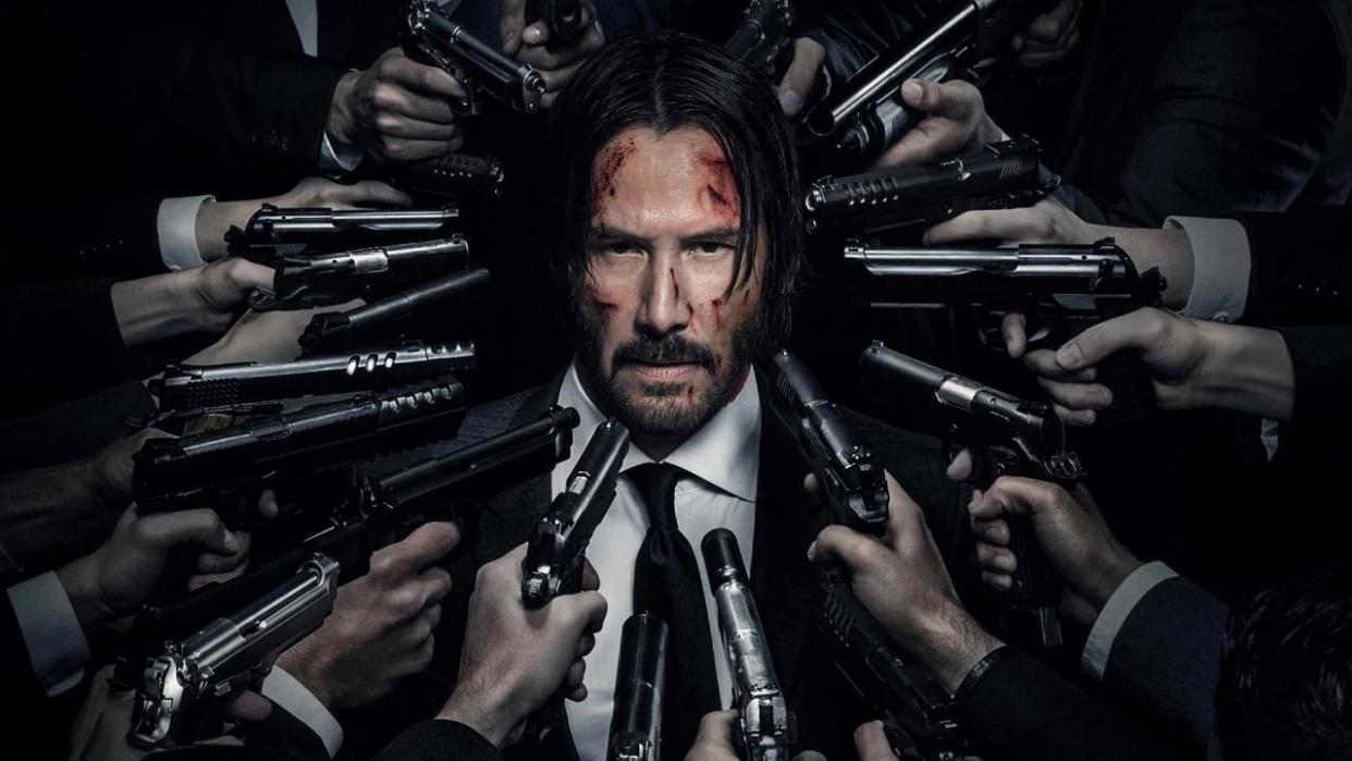  Keanu Reeves as John Wick with guns pointed at him. 