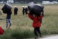 A refugee boy carries his belongings during a police operation at a refugee camp at the border between Greece and Macedonia, near the village of Idomeni, Greece, 24 May 2016 REUTERS/Yannis Kolesidis/Pool