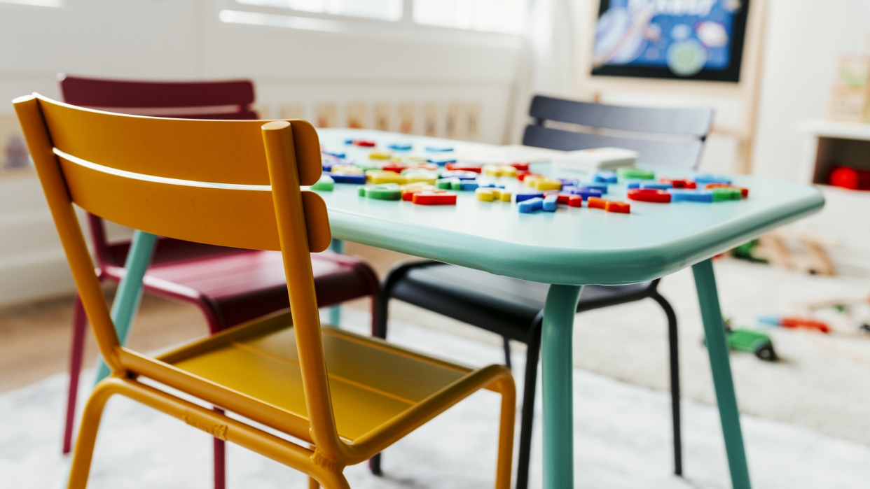 A child's chair and desk with letters on it in a classroom.