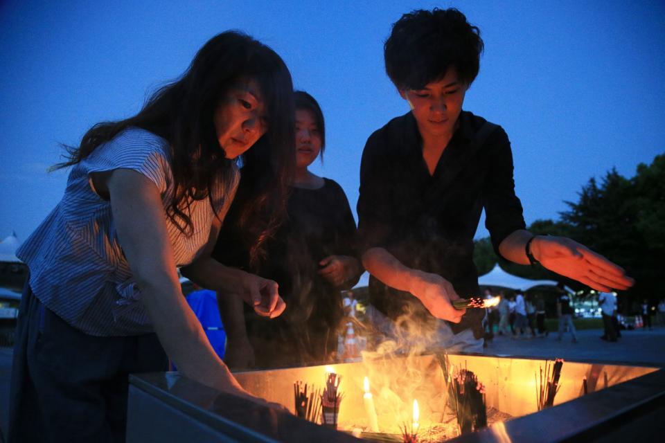 <p>People burn incense and offer prayers early morning prior to the 72nd anniversary memorial service for the atomic bomb victims at the Peace Memorial Park in Hiroshima on Aug. 6, 2017. (Photo: STR/AFP/Getty Images) </p>