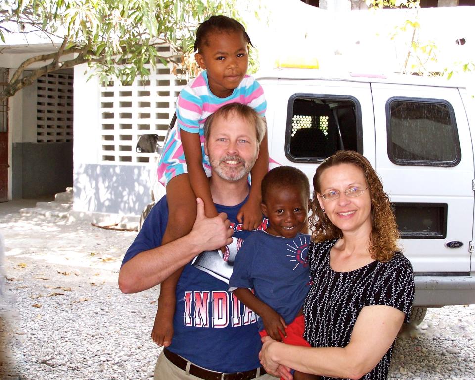 Rev. Chuck Whited and his wife Susan in Haiti in 2004 with the children they would later adopt, Lovelie and Wisken.