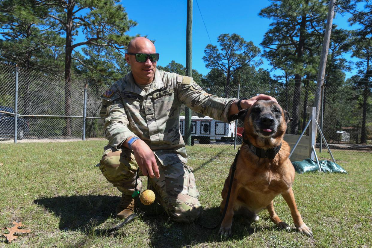 Alijah Springer poses for a portrait with retired dog Alex on Fort Eisenhower on Friday, March 29, 2024.