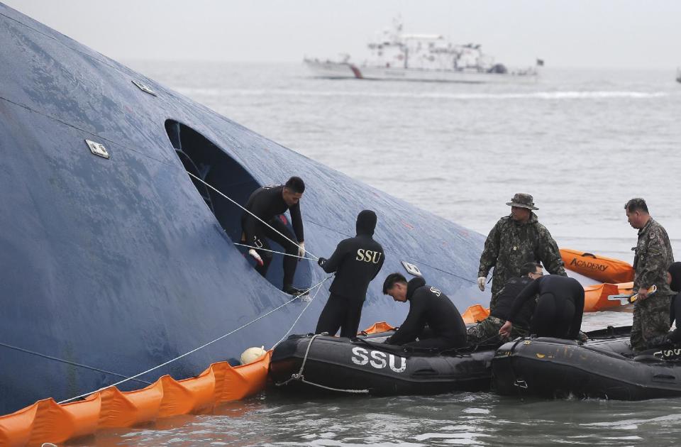 In this Thursday, April 17, 2014, photo, South Korean rescue team members try to rescue passengers trapped in the ferry Sewol sinking in the water off South Korea's southern coast near Jindo. Investigations into South Korea's ferry disaster focused on the sharp turn it took just before it started listing and on the possibility that a quicker evacuation order by the captain could have saved lives, officials said Friday, as rescuers scrambled to find some 270 people still missing and feared dead. (AP Photo/Yonhap) KOREA OUT