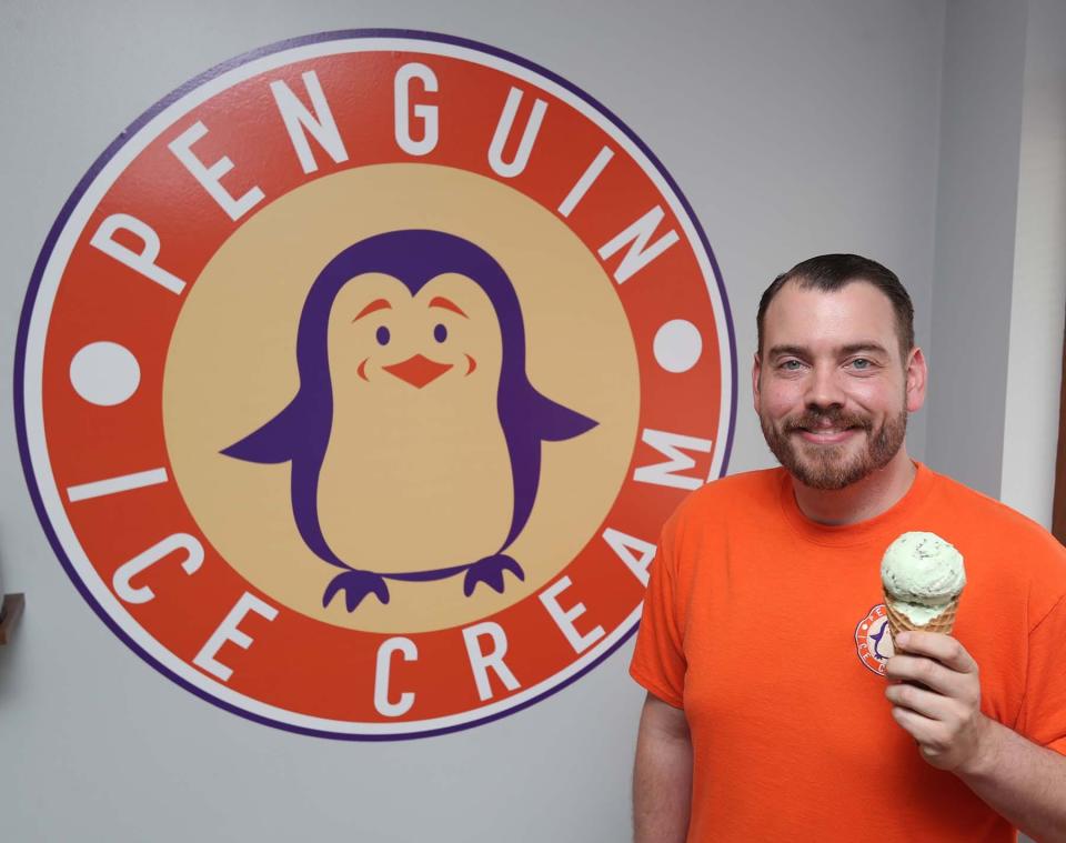 Travis Monty-Bromer, the owner of Penguin Ice Cream in Copley, holds a waffle cone of chocolate mint ice cream.