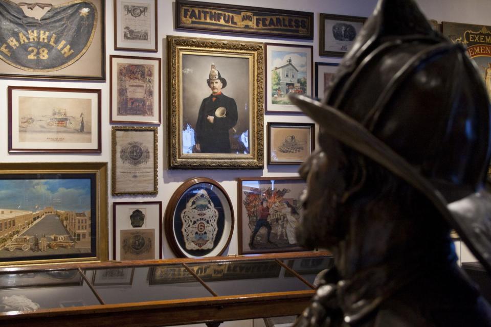 a black firefighter statue in front of a wall with pictures