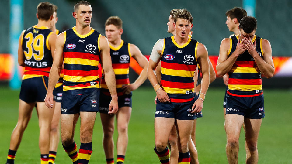 Adelaide Crows players, pictured here walking from the ground looking dejected.