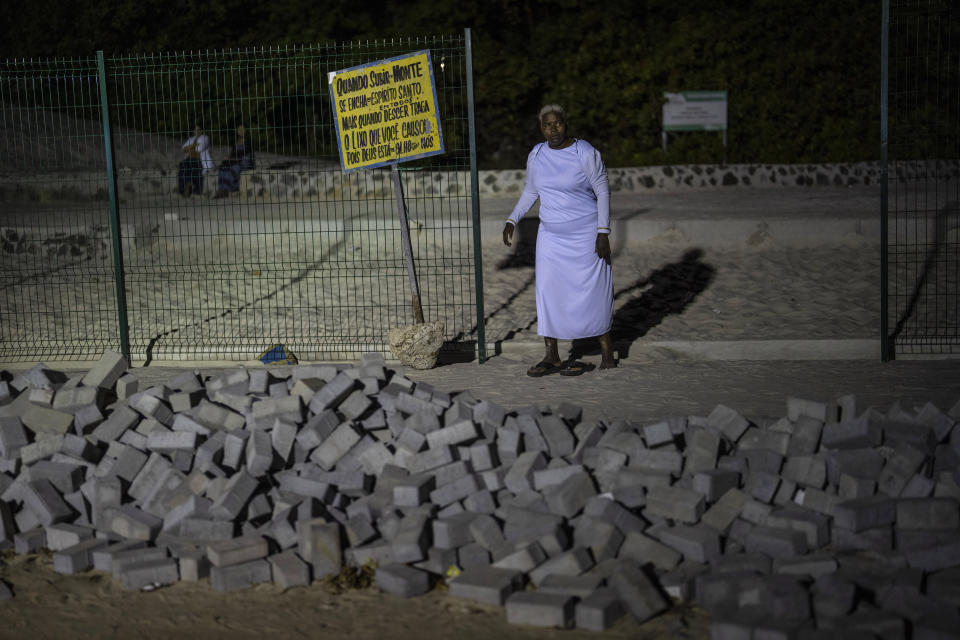 A woman slips on her sandals after descending a steep rise of the Abaete dune system evangelicals have come to call the "Holy Mountain", in Salvador, Brazil, Friday, Sept. 16, 2022. Evangelicals have been converging on the dunes for some 25 years but especially lately, with thousands now coming each week to sing, pray and enter trancelike states to commune with God. (AP Photo/Rodrigo Abd)