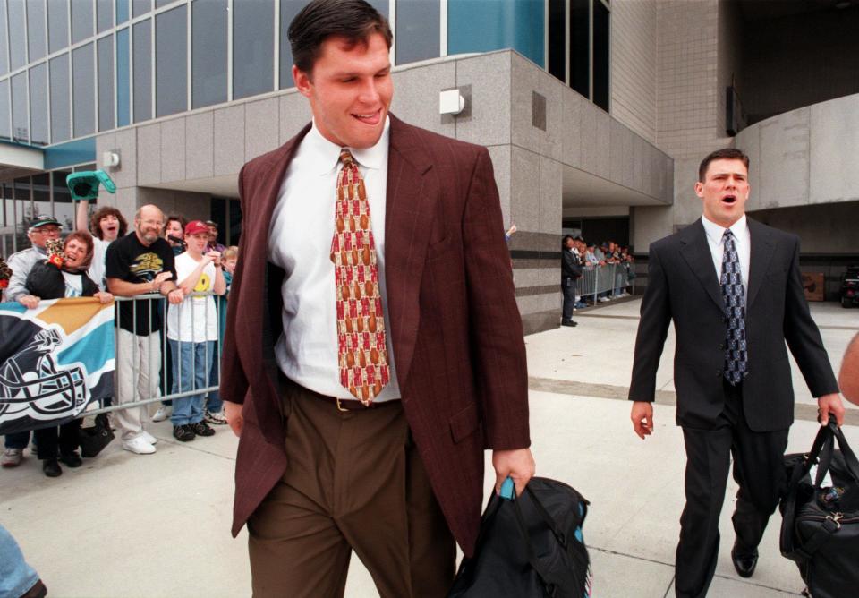 Jacksonville Jaguars players Tony Boselli, left, and Mark Brunell leave the stadium, Dec. 27, 1996, on their way to the flight for a playoff game in Buffalo, as fans cheer them on.
