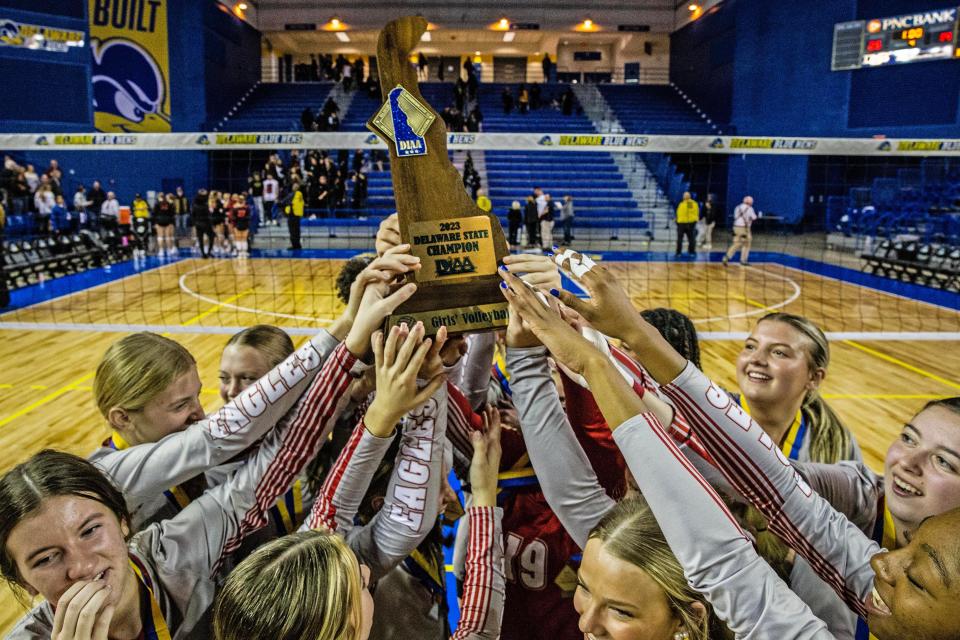 Champions Smyrna High School team members hold up their trophy after their 25-14 victory over Ursuline Academy at the DIAA Girls Volleyball Tournament championship game at the Bob Carpenter Center in Newark, Thursday, Nov. 16, 2023.