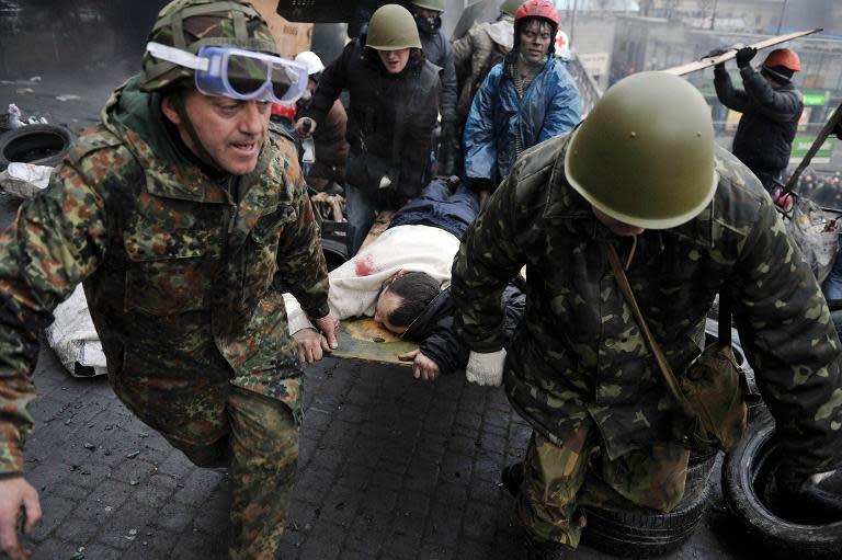 Protesters carry a wounded protester during clashes in Kiev on February 20, 2014