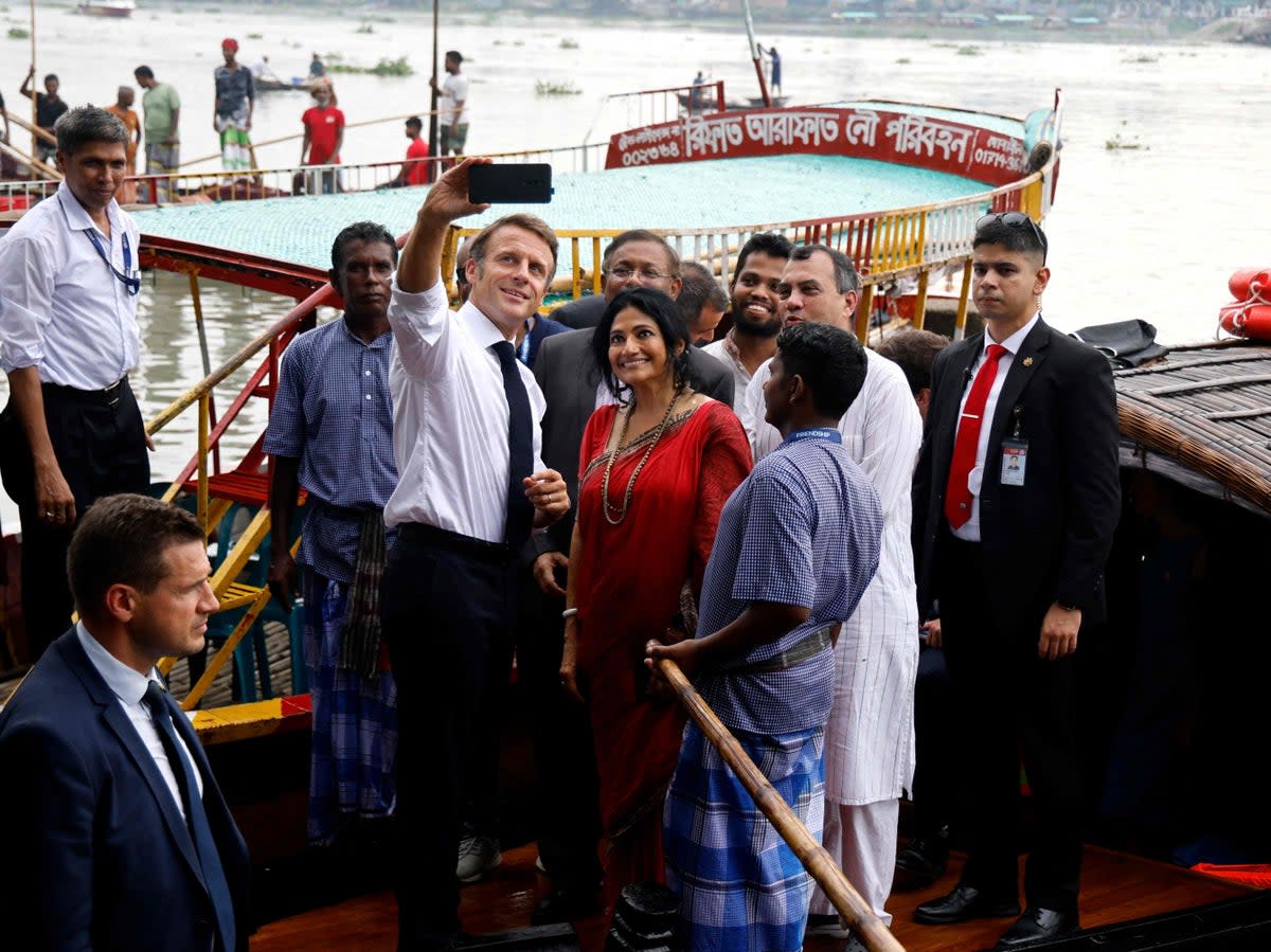France’s President Emmanuel Macron (C) takes a selfie with Bangladeshi locals and members of an NGO after a boat ride during his two-day visit in Dhaka (AFP via Getty Images)