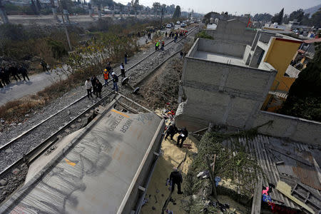 Security forces and railroad workers stand next to the car of a cargo train that ran off the tracks knocking a home in the municipality of Ecatepec, on the outskirts of Mexico City, Mexico January 18, 2018. REUTERS/Daniel Becerril