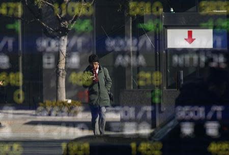 A man is reflected in a stock quotation board outside a brokerage in Tokyo January 28, 2014. REUTERS/Toru Hanai