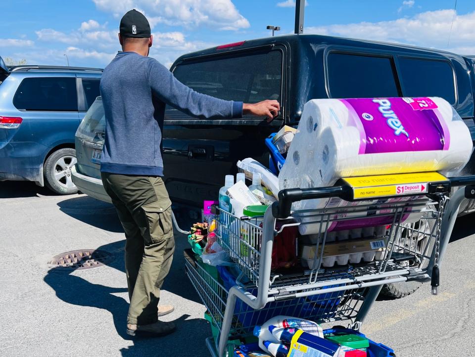 a full cart of groceries with the writer's husband about to open the trunk of his car