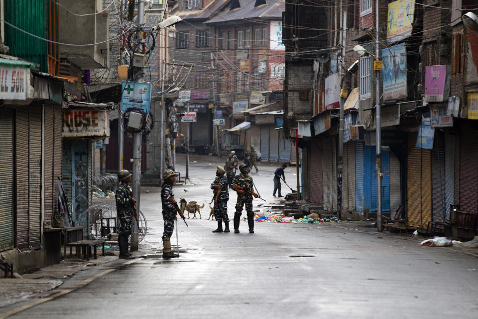 FILE- In this Aug. 8, 2019, file photo, Indian paramilitary soldiers stand guard on a deserted street during curfew in Srinagar, Indian controlled Kashmir. The beautiful Himalayan valley is flooded with soldiers and roadblocks of razor wire. Phone lines are cut, internet connections switched off, politicians arrested. Narendra Modi, the prime minister of the world’s largest democracy has clamped down on Kashmir to near-totalitarian levels. (AP Photo/Dar Yasin, file)