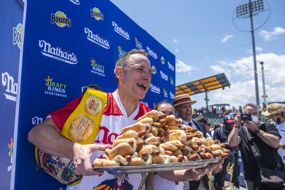 Winners Joey Chestnut and Michelle Lesco, obscured behind hot dogs, pose at the Nathan's Famous Fourth of July International Hot Dog-Eating Contest in Coney Island's Maimonides Park on Sunday, July 4, 2021, in the Brooklyn borough of New York. (AP Photo/Brittainy Newman)