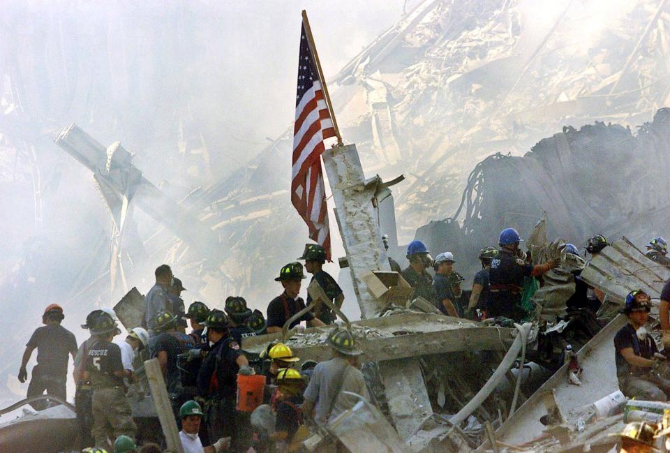 Rescue crews congregate near a U.S. flag amidst the rubble of the World Trade Center in New York in this September 13, 2001 file photo. September 11th marks the 20th anniversary of the 9/11 attacks where nearly 3,000 people died when four hijacked airliners were used in coordinated strikes on the Pentagon and the World Trade Center towers. The fourth plane crashed in Pennsylvania.