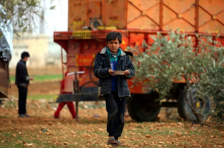 A displaced Syrian boy walks with a plate in Kharufiyah, 18 kilometres south of Manbij, on March 4, 2017