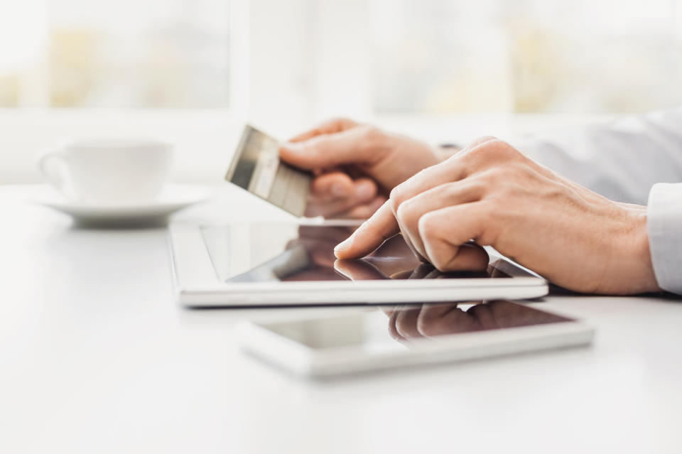 Person using a tablet and holding a credit card.