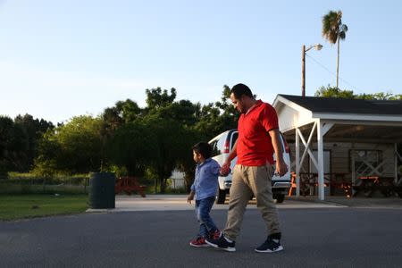 Walter Armando Jimenez Melendez, an asylum seeker from El Salvador, walks with his four year-old son Jeremy at La Posada Providencia shelter in San Benito, Texas, U.S., shortly after he said they were reunited following separation since late May while in detention July 10, 2018. REUTERS/Loren Elliott