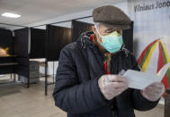 A Lithuanian man reads a ballot paper at a polling station during the second round of a parliamentary election in Vilnius, Lithuania, Sunday, Oct. 25, 2020. Polls opened Sunday for the run-off of national election in Lithuania, where the vote is expected to bring about a change of government following the first round, held on Oct. 11, which gave the three opposition, center-right parties a combined lead. (AP Photo/Mindaugas Kulbis)