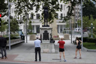 People look at a new black resin and steel statue entitled "A Surge of Power (Jen Reid) 2020" by artist Marc Quinn after it was put up this morning on the empty plinth of the toppled statue of 17th century slave trader Edward Colston, which was pulled down during a Black Lives Matter protest in Bristol, England, Wednesday, July 15, 2020. On June 7 anti-racism demonstrators pulled the 18-foot (5.5 meter) bronze likeness of Colston down, dragged it to the nearby harbor and dumped it in the River Avon — sparking both delight and dismay in Britain and beyond. (AP Photo/Matt Dunham)