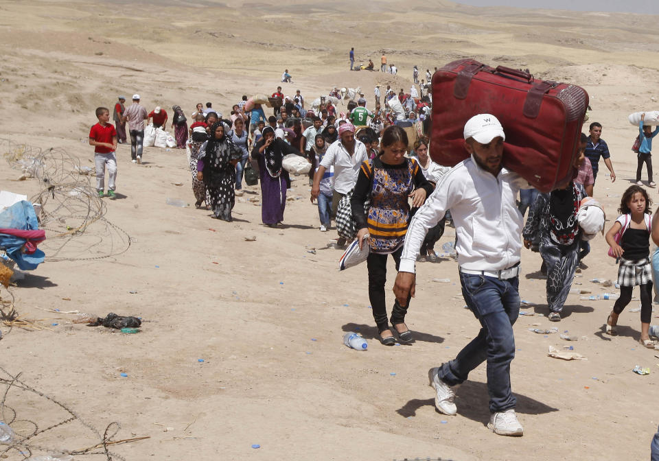 FILE - Syrian refugees cross into Iraq at the Peshkhabour border point in Dahuk, 260 miles (430 kilometers) northwest of Baghdad, Iraq, Aug. 20, 2013. Ten years after the Islamic State group declared its caliphate in large parts of Iraq and Syria, the extremists now control no land, have lost many prominent founding leaders and are mostly away from the world news headlines. (AP Photo/Hadi Mizban, File)