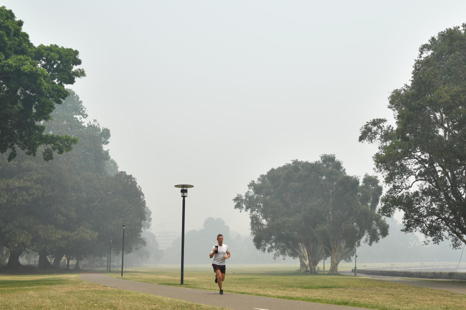 A man runs through Rushcutters Bay Park as smoke haze from bushfires in New South Wales blankets the CBD in Sydney.