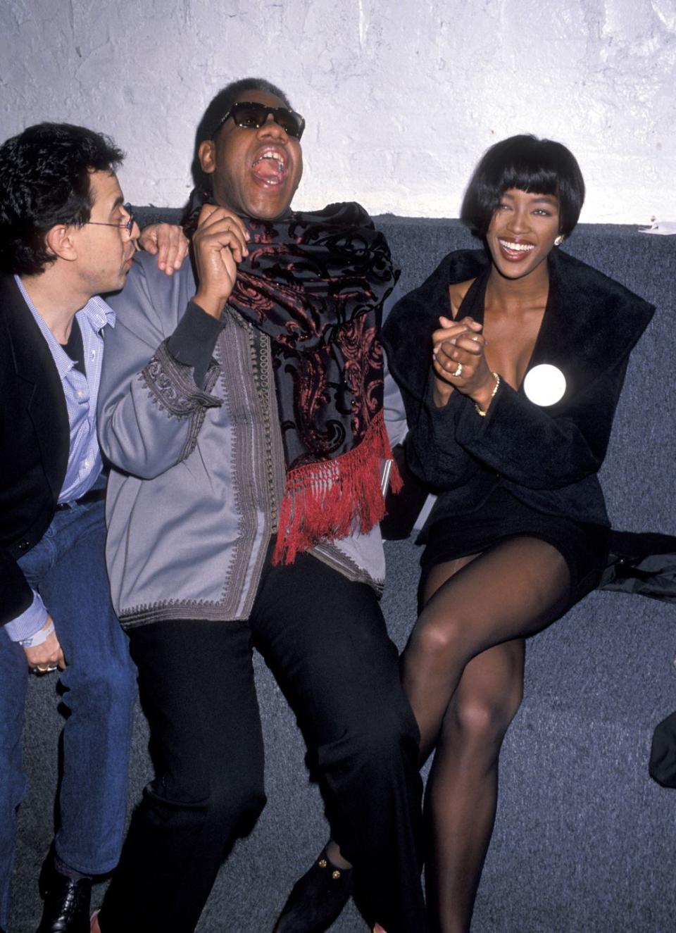 <p>Talley shares a laugh with supermodel Naomi Campbell at a party, rocking his signature black sunglasses on top of a formal suit. </p>