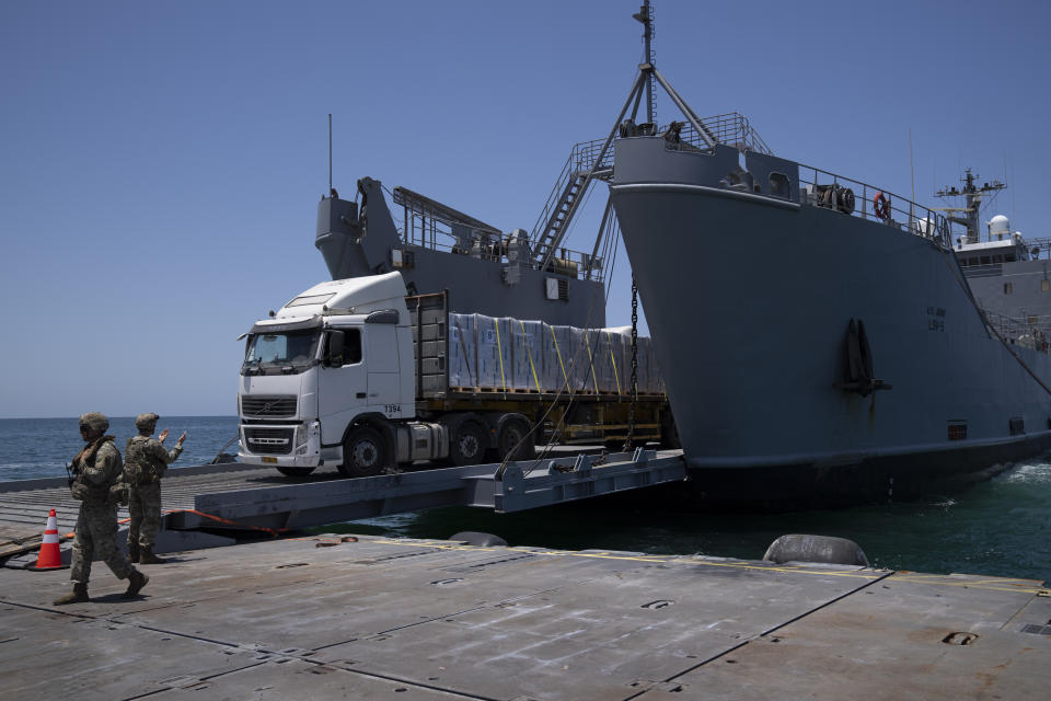 A U.S. Army soldier gestures as trucks loaded with humanitarian aid arrive at the U.S.-built floating pier Trident before reaching the beach on the coast of the Gaza Strip, Tuesday, June 25, 2024. (AP Photo/Leo Correa)