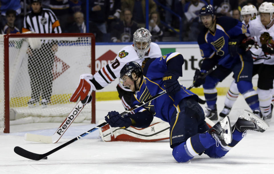 St. Louis Blues' T.J. Oshie, front, reaches for a puck to score past Chicago Blackhawks goalie Corey Crawford during the second period in Game 5 of a first-round NHL hockey playoff series Friday, April 25, 2014, in St. Louis. (AP Photo/Jeff Roberson)
