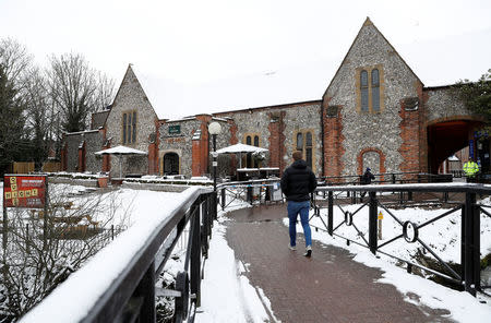 People walk past police tape placed around a pub which was visited by former Russian intelligence officer Sergei Skripal and his daughter Yulia before they were found on a park bench after being poisoned in Salisbury, Britain, March 19, 2018. REUTERS/Peter Nicholls