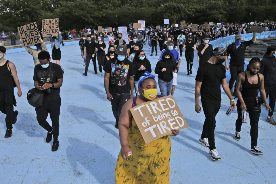 Protesters march around large sculpture of a globe in Flushing Meadows Corona Park in the Queens borough of New York, Sunday, May 31, 2020. Demonstrators took to the streets to protest the death of George Floyd, who died May 25 after he was pinned at the neck by a Minneapolis police officer. (AP Photo/Seth Wenig)