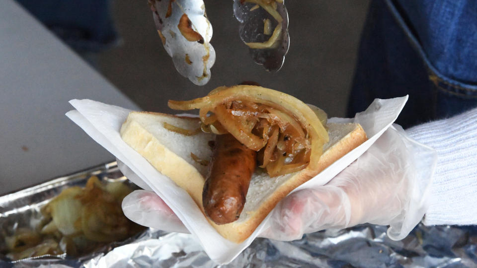 An election volunteer serves a sausage sandwich with onions during today's Federal Election. 