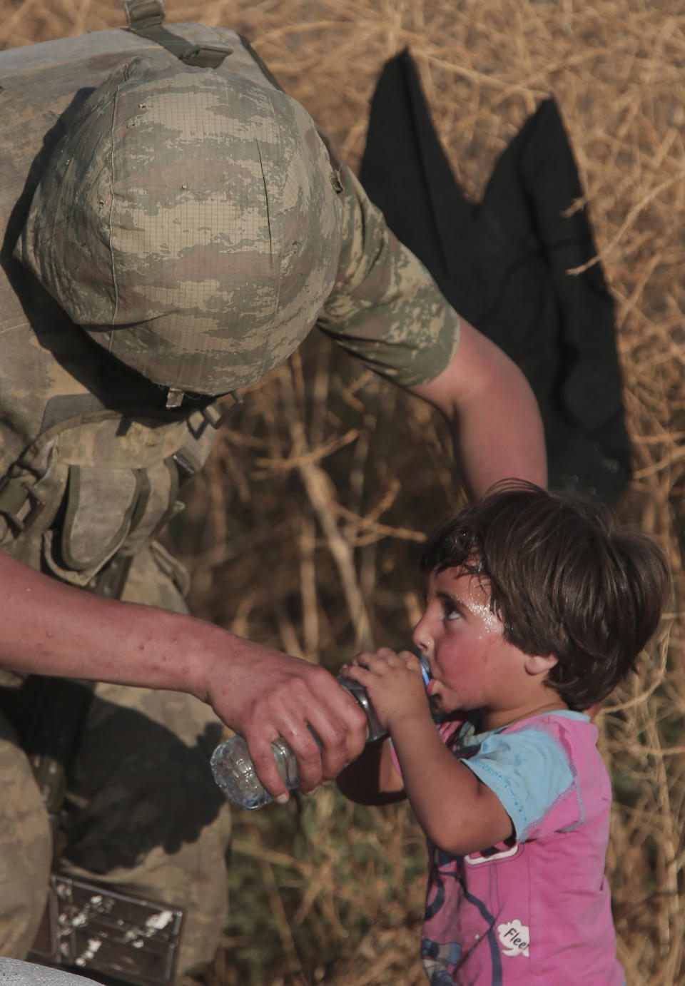 File - In this June 14, 2015, file photo a Turkish soldier offers water to a Syrian refugee child after crossing into Turkey from Syria, in Akcakale, Sanliurfa province, southeastern Turkey. As Turkish forces invaded northern Syria in early October 2019, supporters of the offensive launched an online misinformation campaign. Dozens of misleading images claiming to show Turkey’s soldiers cuddling babies, feeding hungry toddlers and carrying elderly women spread across Twitter and Instagram where they were liked, retweeted and viewed thousands of times. They included this photo, which was, in fact, shot by an Associated Press photographer in 2015. (AP Photo/Lefteris Pitarakis, File)