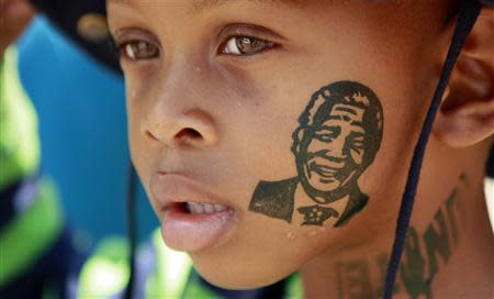 A boy is seen with an image of former South African President Nelson Mandela printed on his face as he queues to view Mandela's body lying in state, outside the Union Buildings in Pretoria, December 11, 2013. REUTERS/Thomas Mukoya