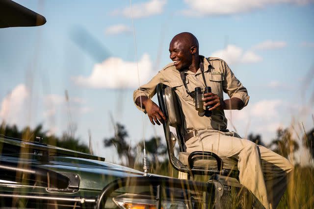 <p>Crookes&Jackson</p> Tracker Kgomotso Batani from andBeyond Xaranna Okavango Delta Camp sits in the raised “spotter” seat of a safari vehicle.