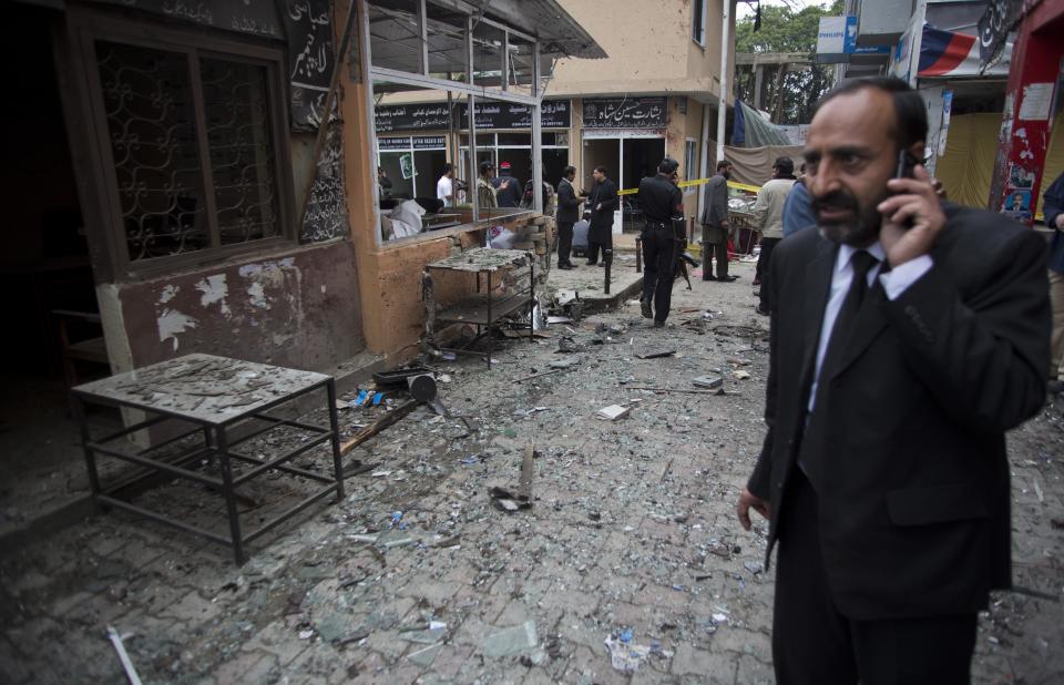 A Pakistani lawyer talks on his mobile phone at the site of a suicide attack in a court complex, Monday, March 3, 2014 in Islamabad, Pakistan. Two suicide bombers blew themselves up at the complex on Monday, killing 11 people and wounding dozens in a rare terror attack in the heart of Islamabad, officials said. (AP Photo/B.K. Bangash)