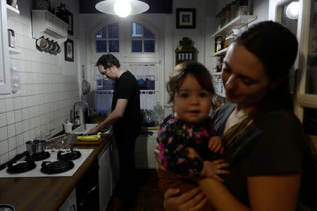 Artist Grzegorz Chudy, 36, cooks at his home as his wife Aleksandra, 36, stands by holding their nine-month-old child Kinga in Nikiszowiec district in Katowice, Poland, November 26, 2018. REUTERS/Kacper Pempel