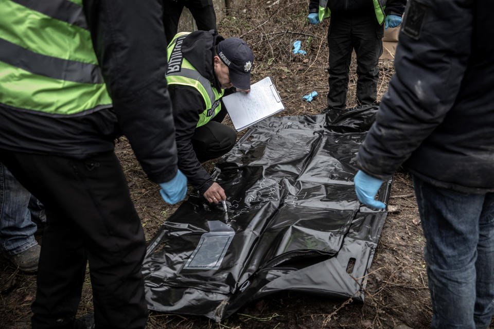 La policía marca una bolsa para cadáveres mientras los investigadores de crímenes de guerra exhuman varios cuerpos de una fosa común en Pravdyne, un pueblo cerca de Jersón, Ucrania, el lunes 28 de noviembre de 2022. (Finbarr O'Reilly/The New York Times).