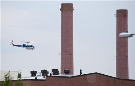 A police helicopter flies overhead as police walk on the roof of a building as they respond to a shooting at the Washington Navy Yard in Washington September 16, 2013. REUTERS/Joshua Roberts