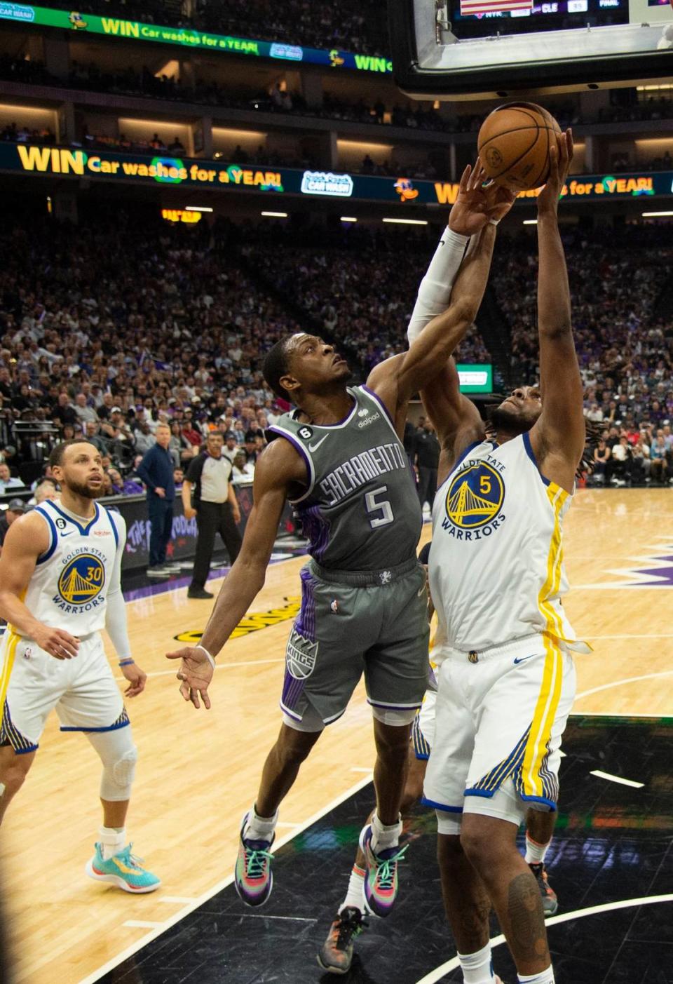 Sacramento Kings guard De’Aaron Fox (5) battles Golden State Warriors forward Kevon Looney (5) for the ball during Game 5 on Wednesday.