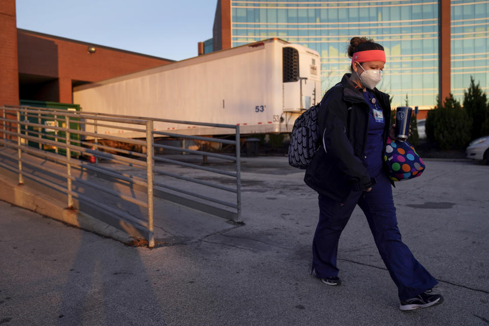 Nurse Jessica Franz walks past a mobile morgue at Olathe Medical Center after working the graveyard shift Thursday, Nov. 26, 2020, in Olathe, Kan. Franz lost her mother-in-law to COVID on Nov. 10 and was planning a scaled-back Thanksgiving with just her household. (AP Photo/Charlie Riedel)