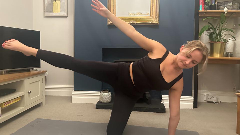 Woman doing a gate pose with her leg lifted in the air.